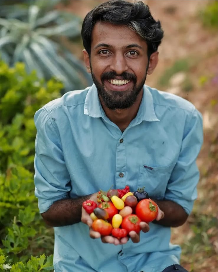 Sooraj C.S., founder of Farm Formulas, holding a harvest of heirloom tomatoes